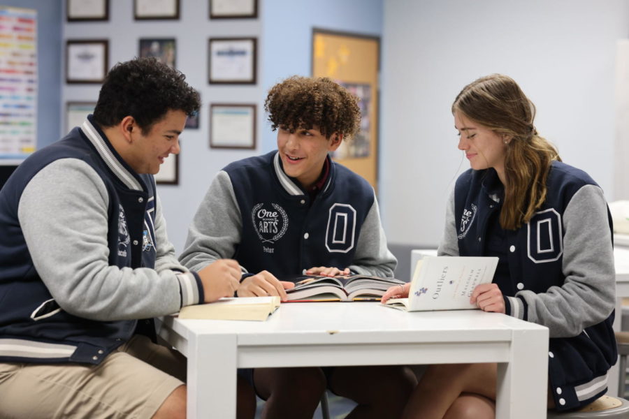 Seniors Jacob Gomez, Peter Fares, and Desiree Mann smile as they sit and work together.