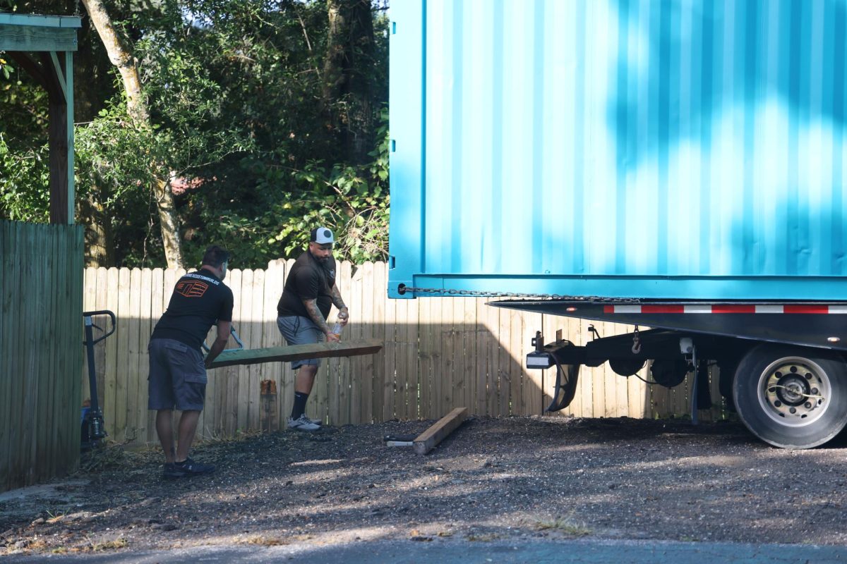 The facilities team sets up the space for the uniform store container. 