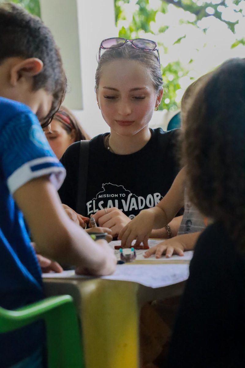 Coloring at the local church, Brianna Eshliman, 12th grade, connects with both the local children and her classmates. 