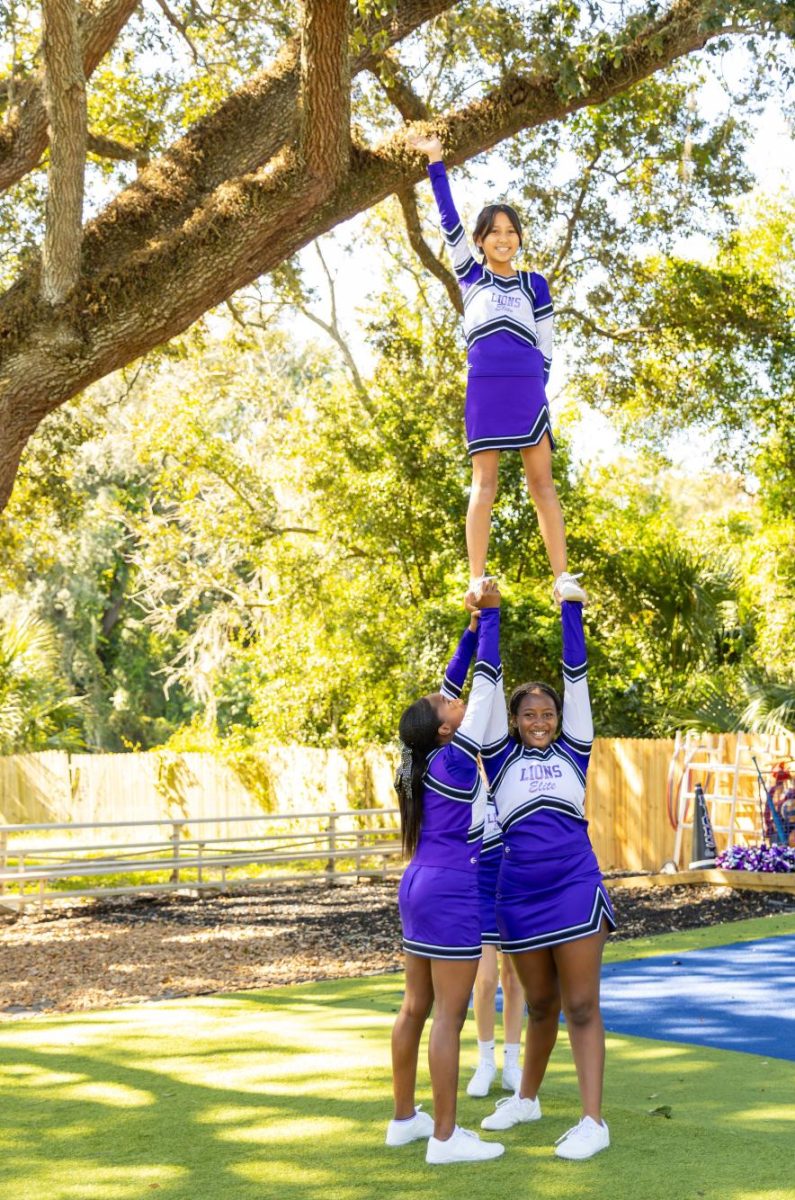 Amaya Lewis and Oni Simone Richmond help hold up Mika Miller as they perform at the pep rally before heading to their first ever competition as a team. 
